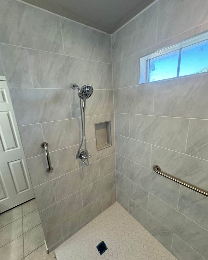 An accessible shower with grab bars, a niche and a transom window
