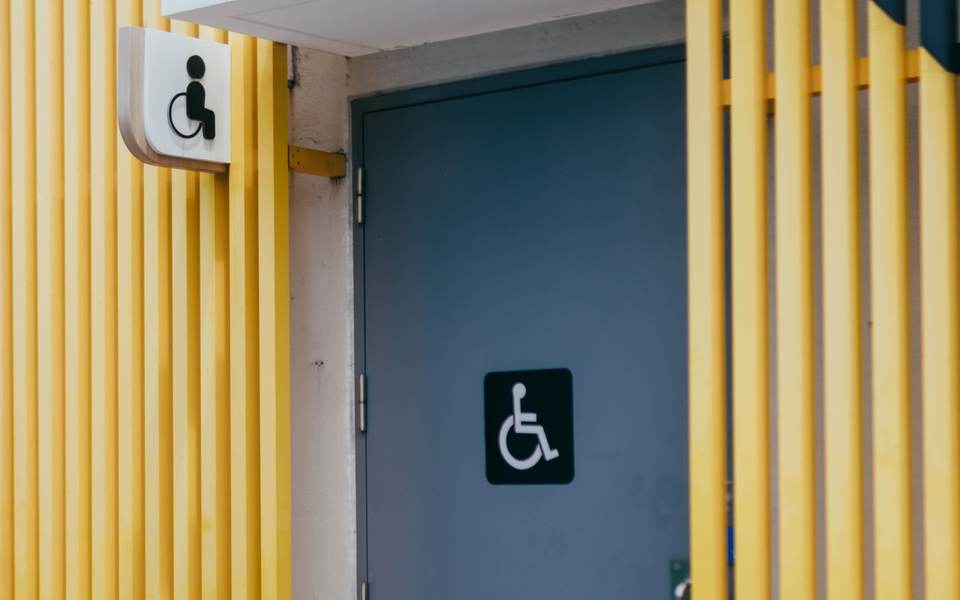 Restroom door with an accessible wheelchair sign beside a yellow slatted wall