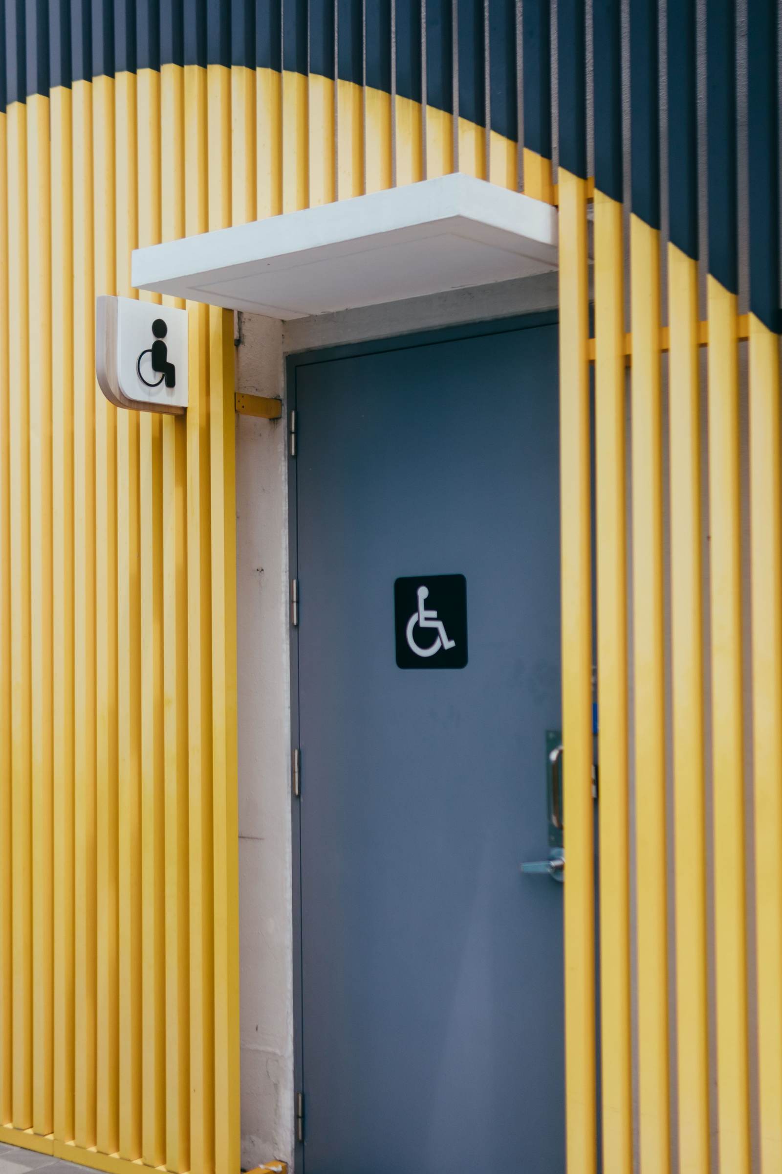 Restroom door with the wheelchair symbol set between yellow wall slats