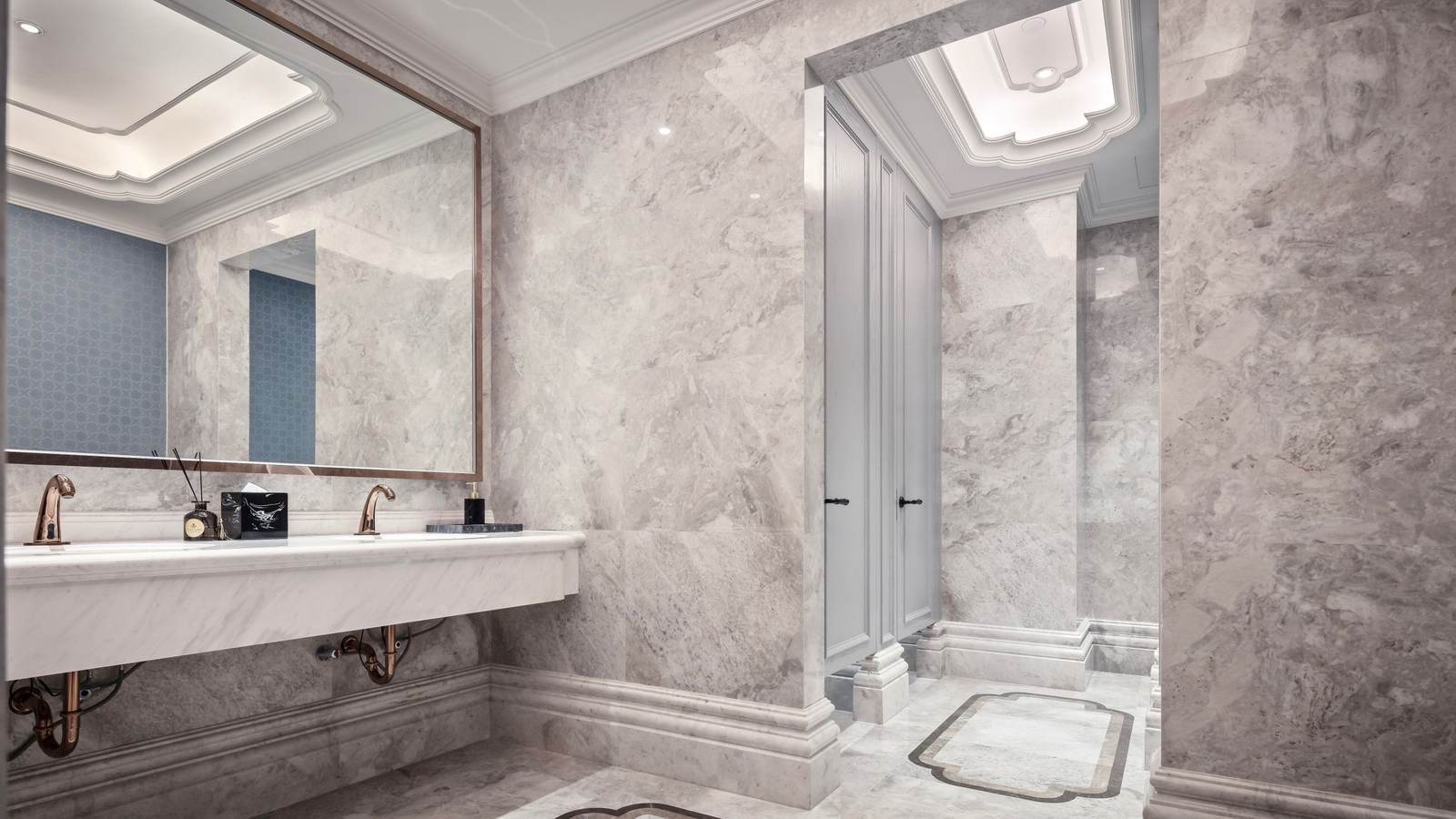 Wall-hung marble restroom counter with open knee space below and brass faucets