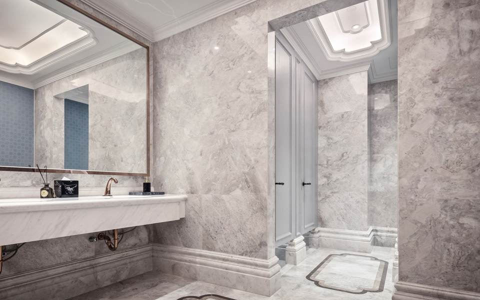 Gray marble restroom with a wall-hung double sink open underneath and a wide mirror