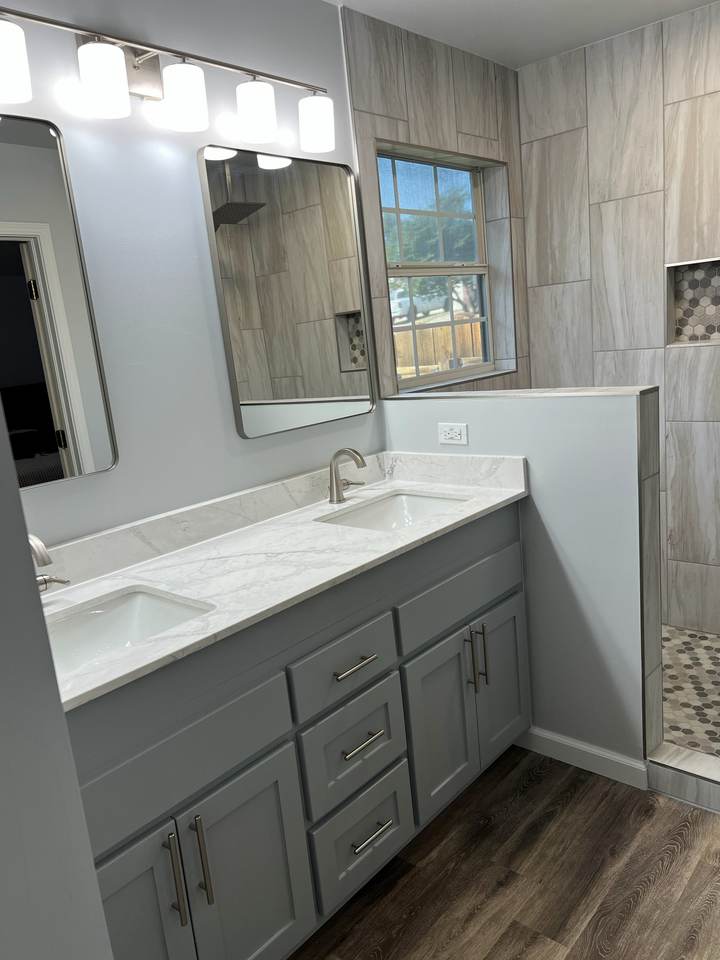 A gray double vanity with black-framed mirrors and a four-light bar