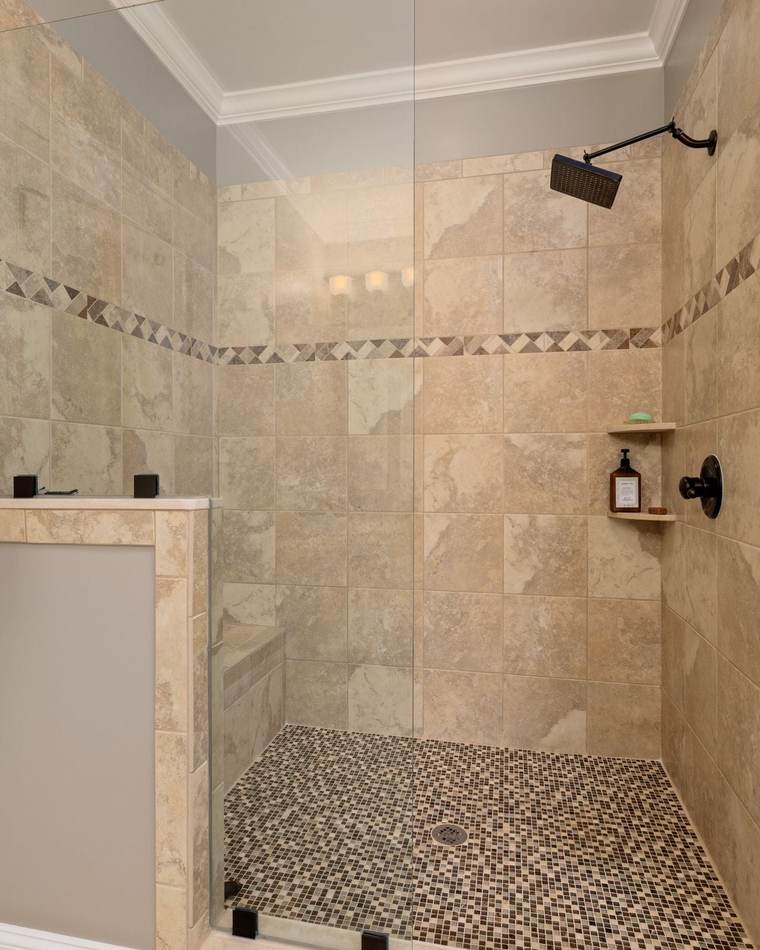 Walk-in shower with beige stone-look wall tile, a diamond border, a tiled bench, a mosaic floor and a frameless glass panel