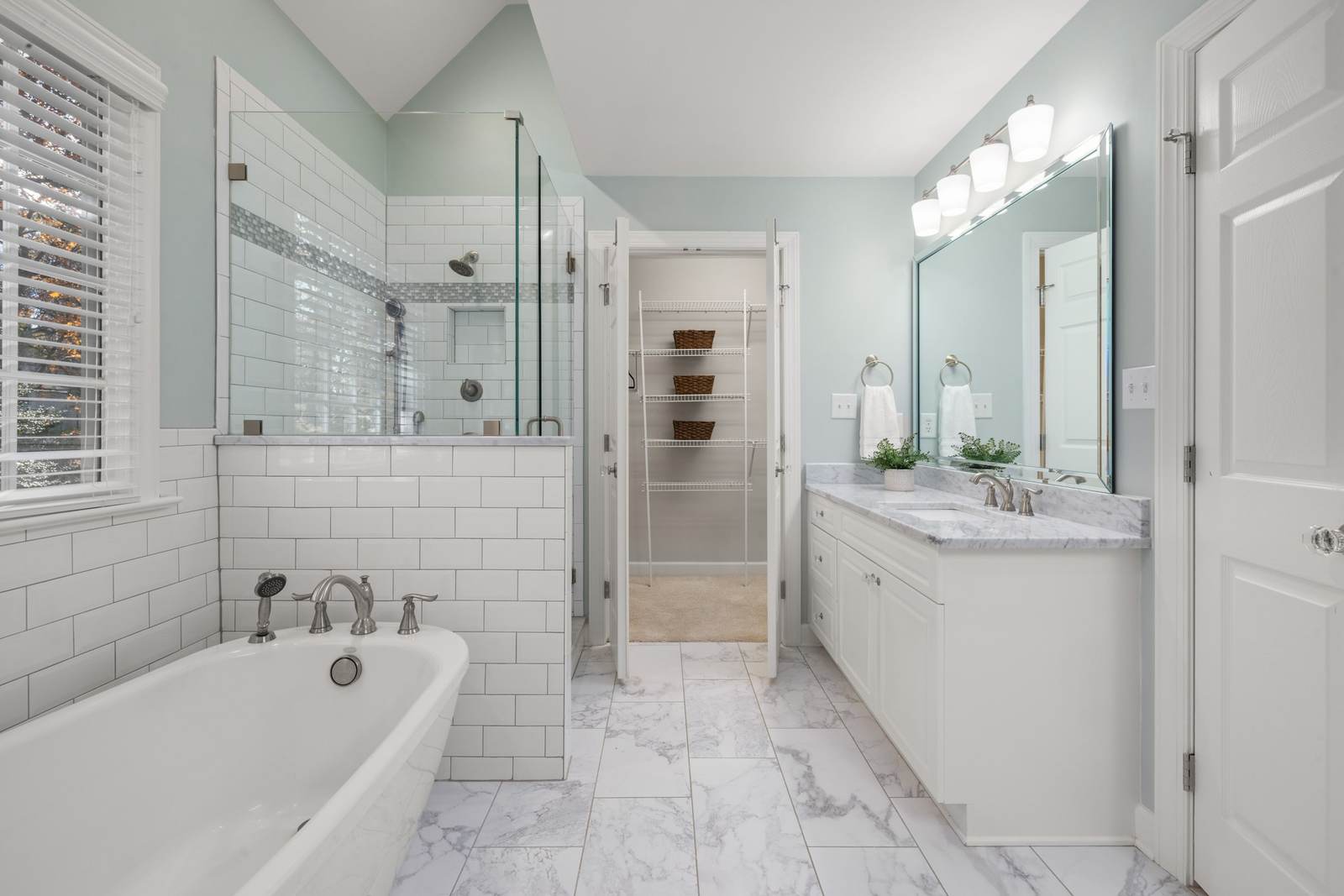 Bathroom with a freestanding tub, white subway tile, and a marble-top vanity
