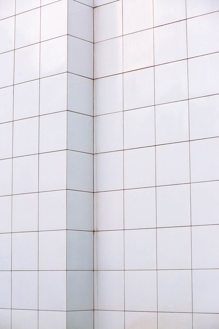 White wall tile with gray grout lines meeting at a corner