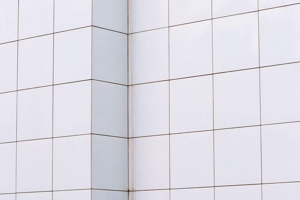 Plain white wall tiles and thin gray grout joints turning an outside corner