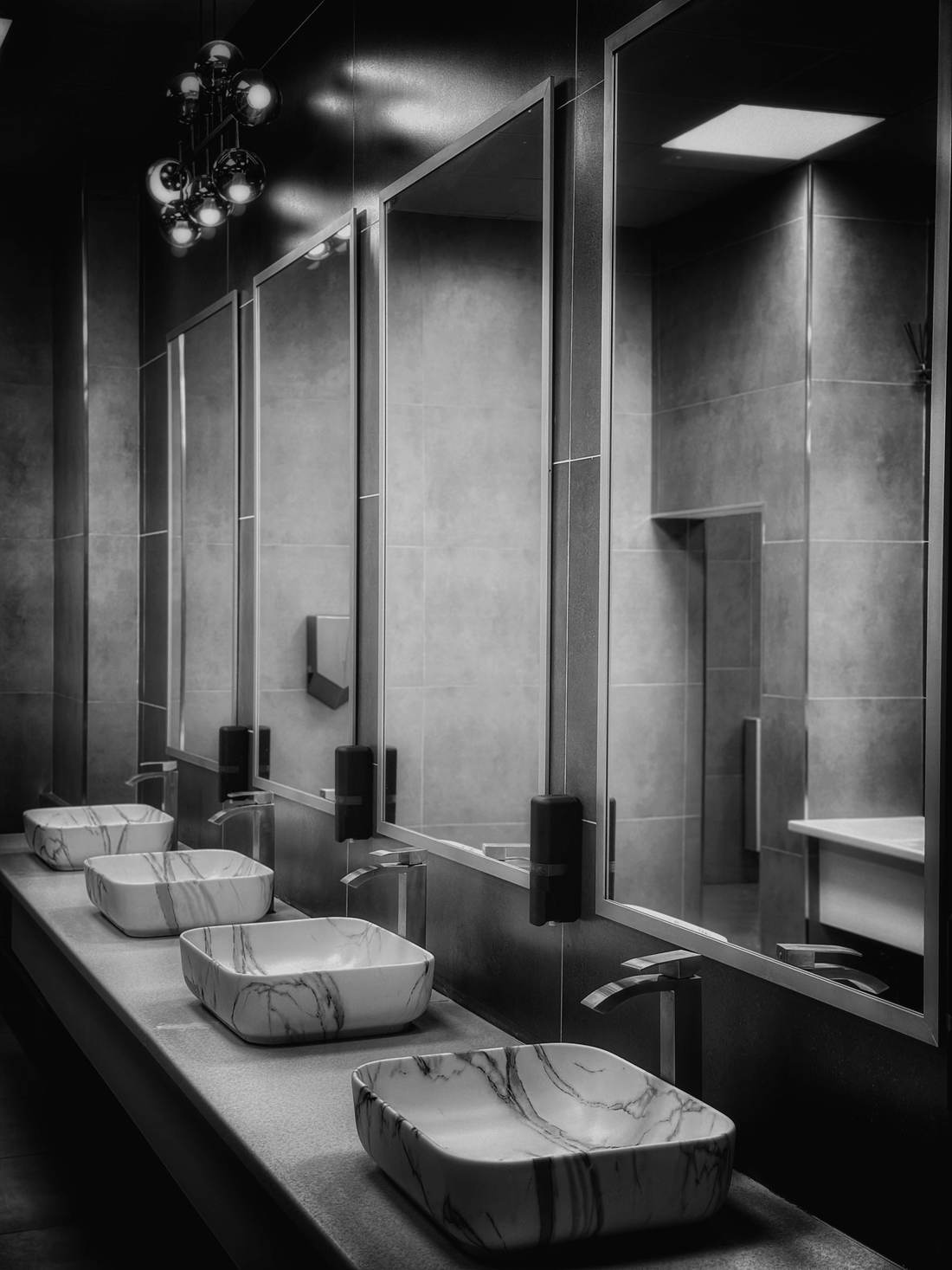 Restroom with gray tile walls, vessel sinks on a dark counter and tall mirrors