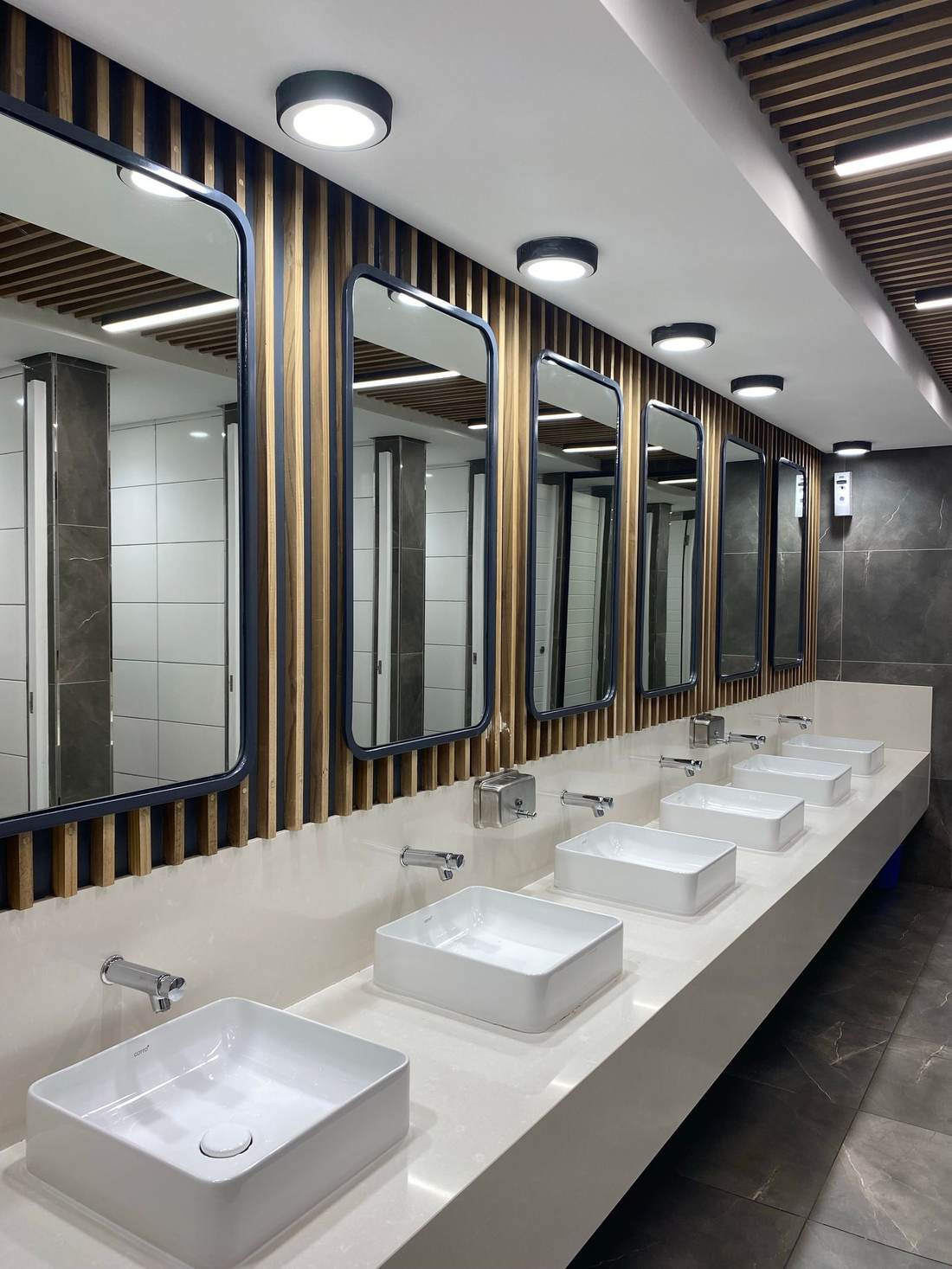 Remodeled commercial restroom with vessel sinks on a long counter and tall mirrors
