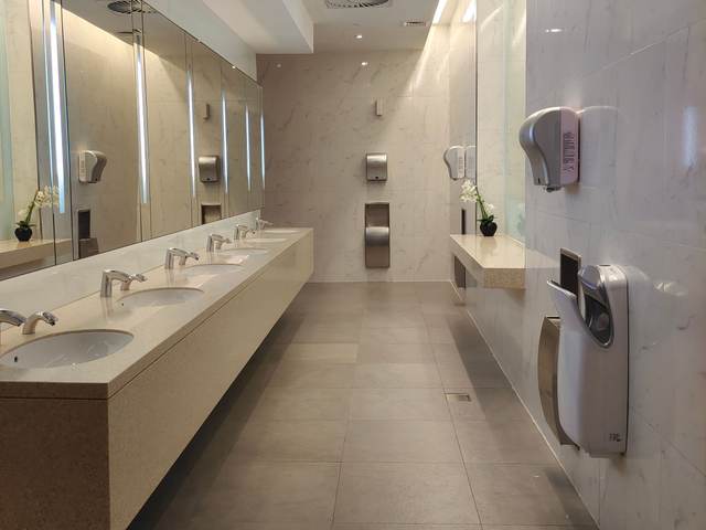 Commercial restroom with a long stone counter, undermount sinks and wall-mounted hand dryers