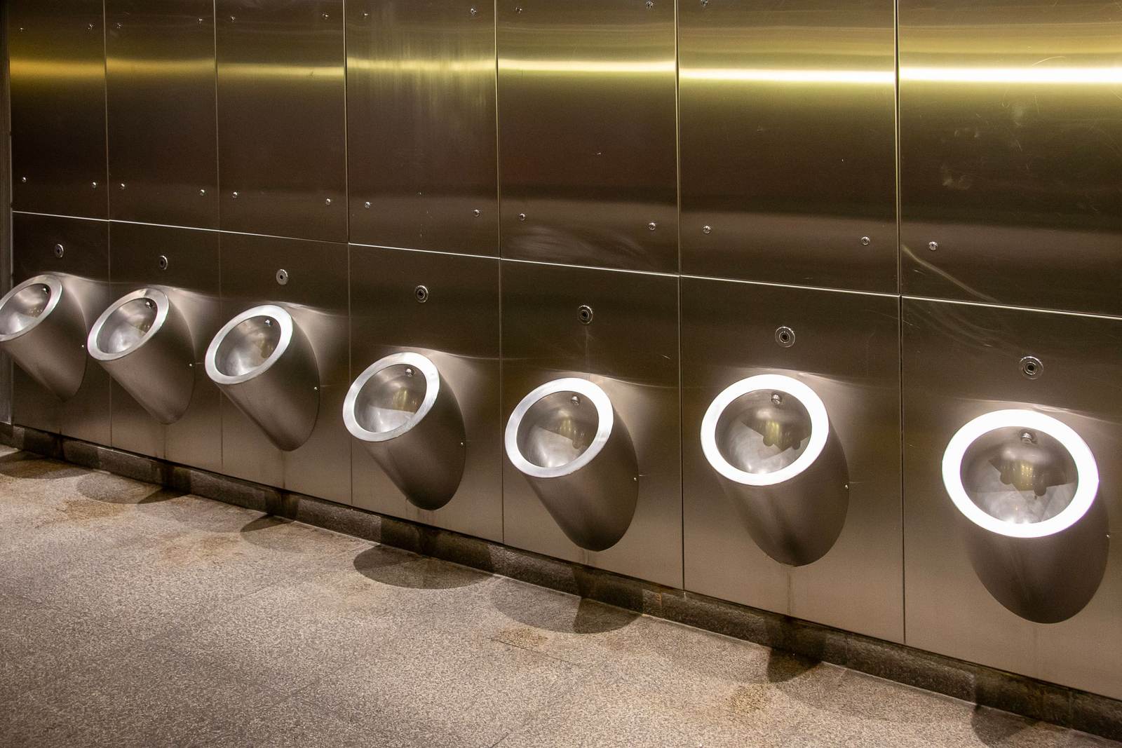 Stainless steel urinals along a commercial restroom wall