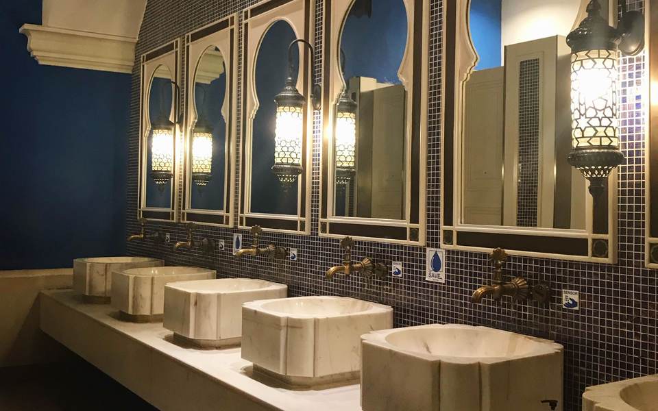 Restaurant restroom with stone vessel sinks under arched mirrors and dark mosaic tile