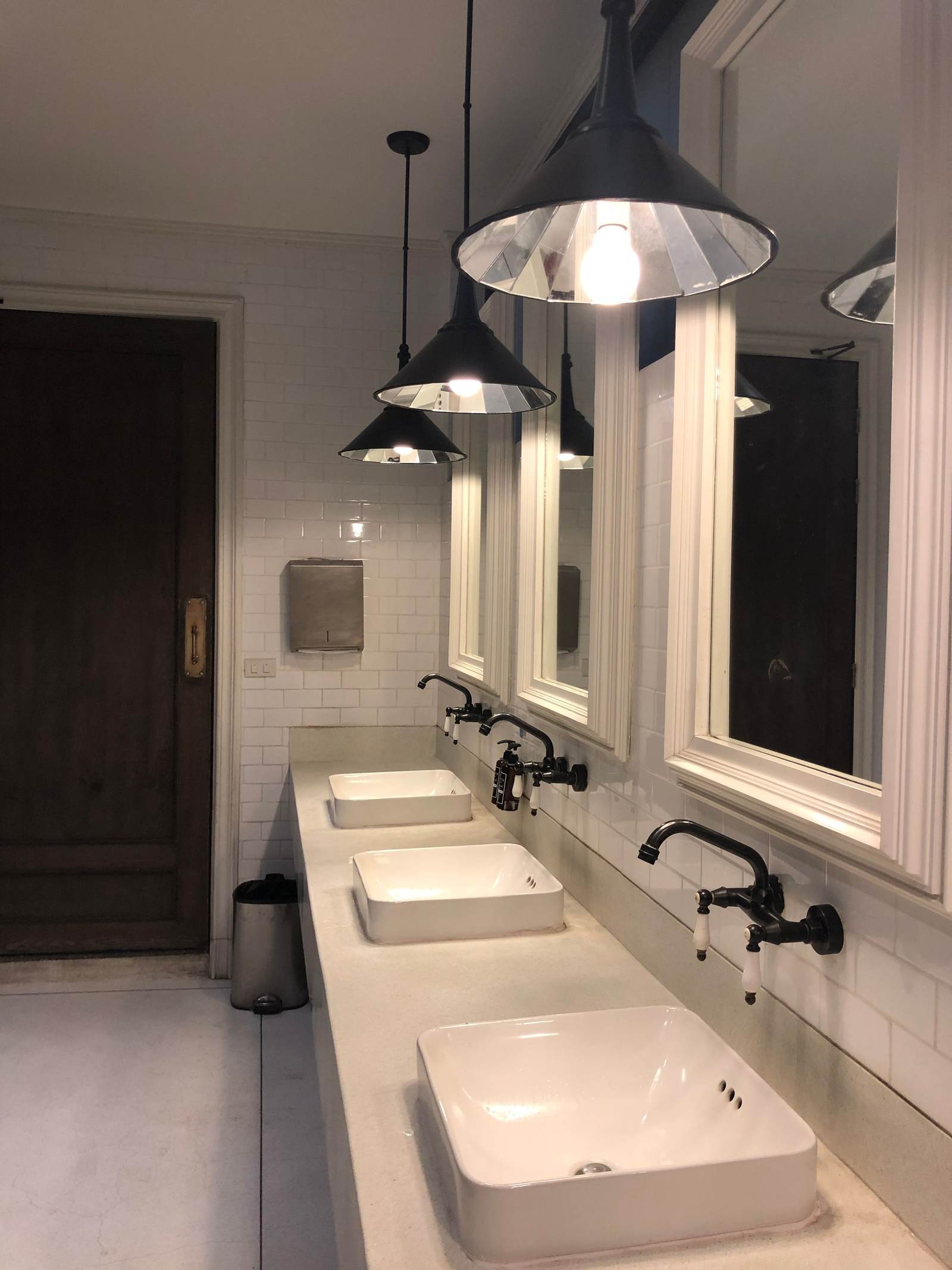 Restroom with white subway tile walls, vessel sinks, framed mirrors and pendant lights