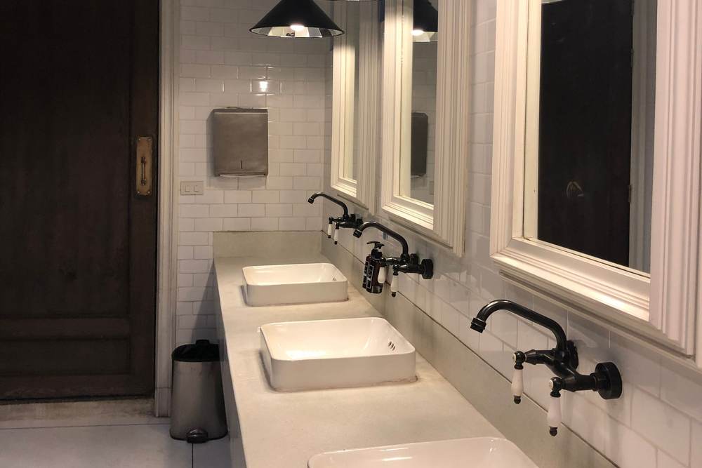 Restroom with white vessel sinks, wall-mounted faucets, framed mirrors and pendant lights