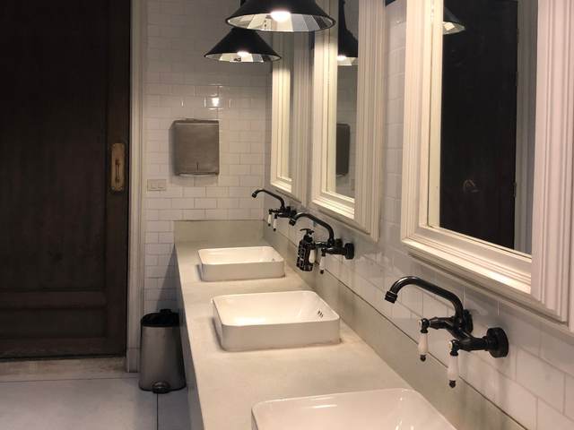 Restroom with white vessel sinks, wall-mounted faucets, framed mirrors, and pendant lights