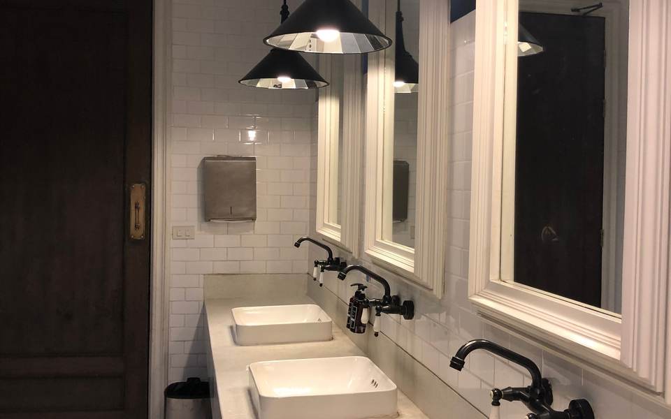 Restroom with white vessel sinks, wall-mounted black faucets, framed mirrors and pendant lights