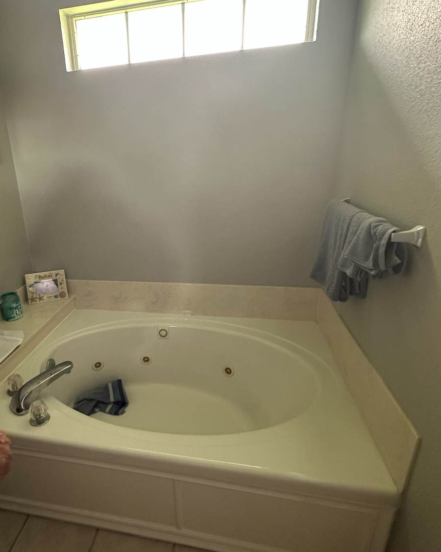 Before: a corner jacuzzi tub under a transom window in a Glenpool bathroom