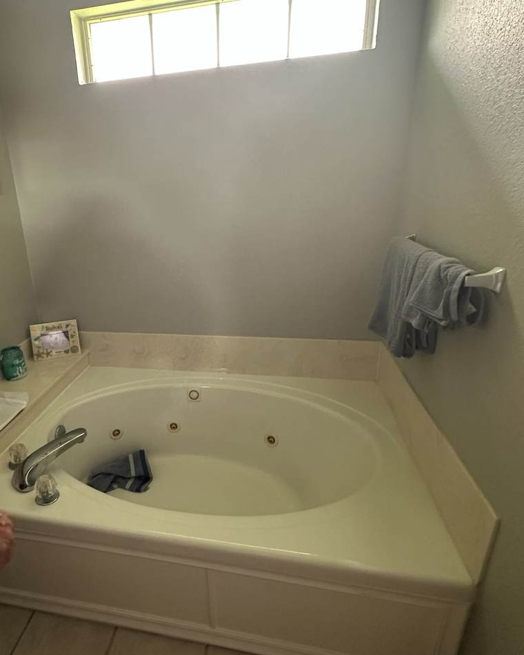 Before: a corner jetted tub under a transom window