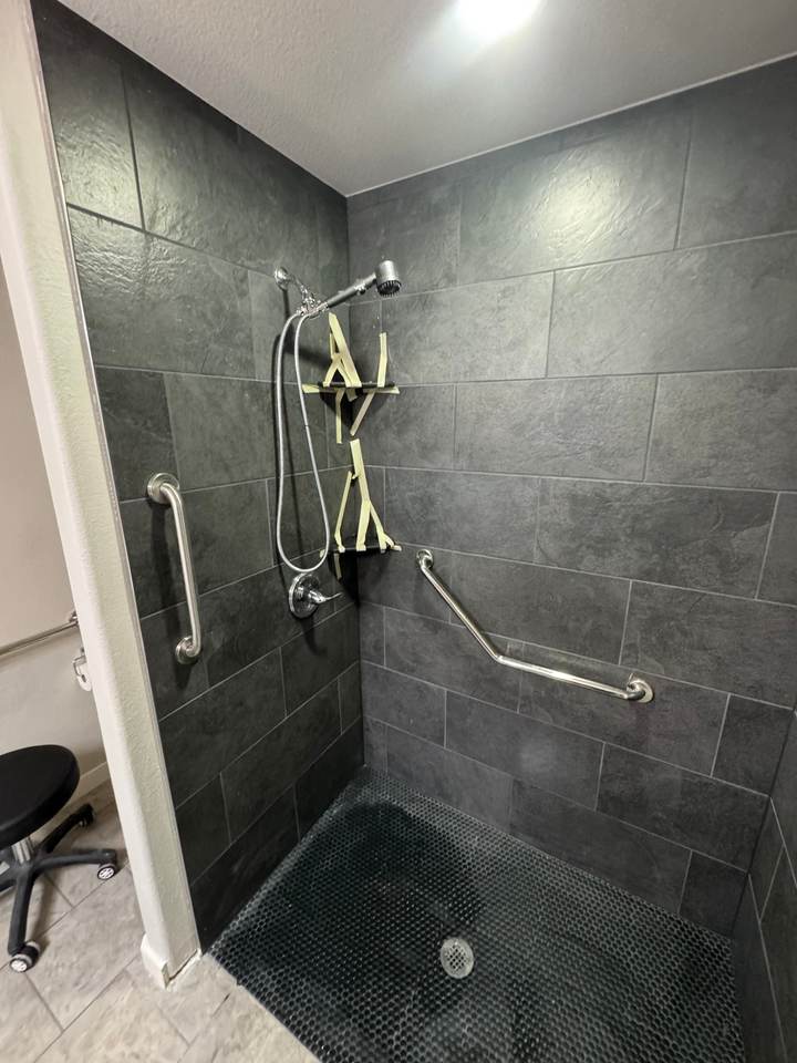 A curbless walk-in shower with slate-look tile and grab bars