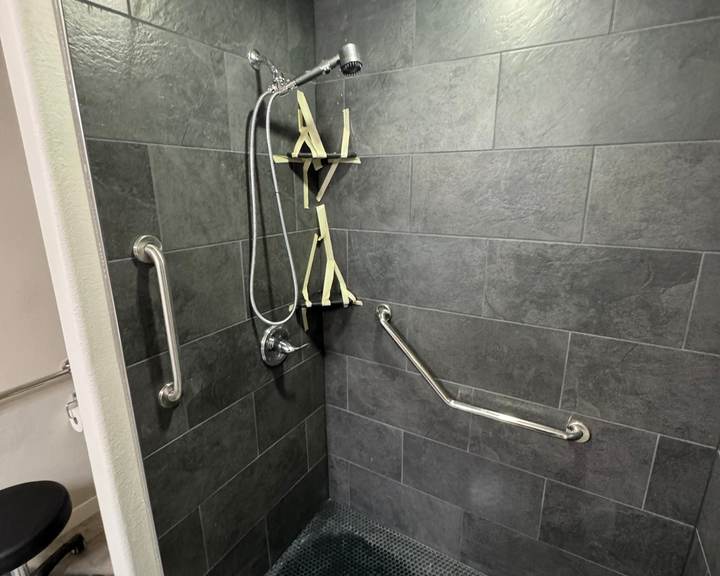 Tiled walk-in shower with slate-look tile, a dark mosaic floor and grab bars in a Bixby master bathroom