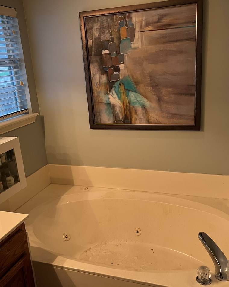 Before: a jetted garden tub under a window beside an oak vanity