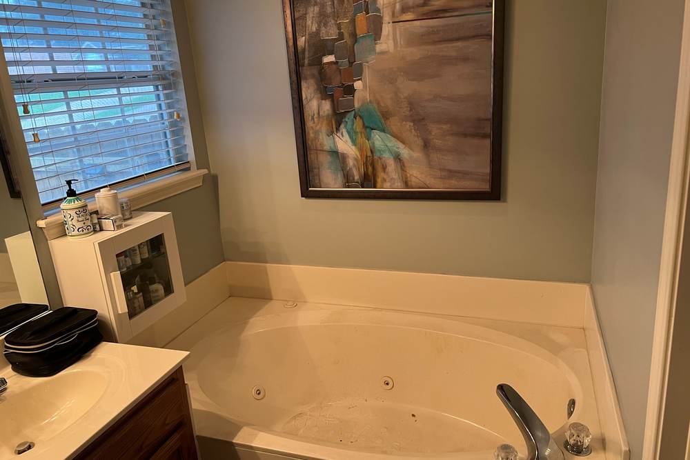 Before: a jetted garden tub under a window in an east Tulsa master bath, the space that became a full tiled walk-in shower