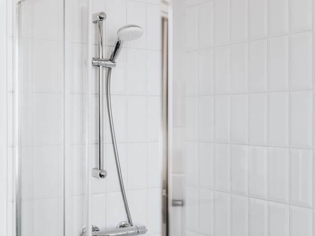 Hand shower on a slide bar on white tile, adjustable for standing or seated use