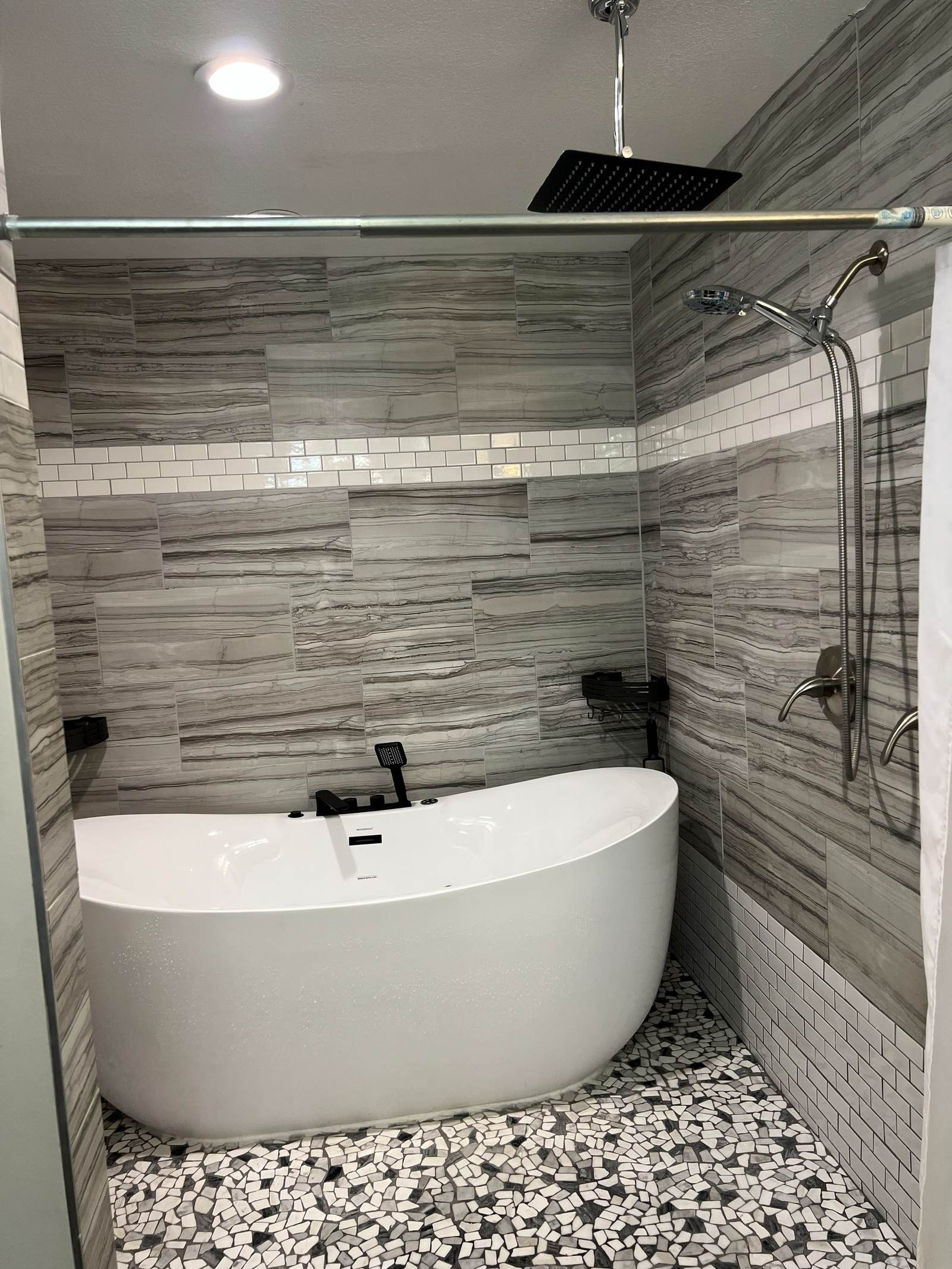 Freestanding soaking tub inside a tiled wet room we built in a south Tulsa bathroom