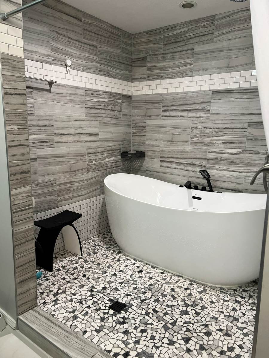 White soaking tub with black fixtures in the finished south Tulsa wet room