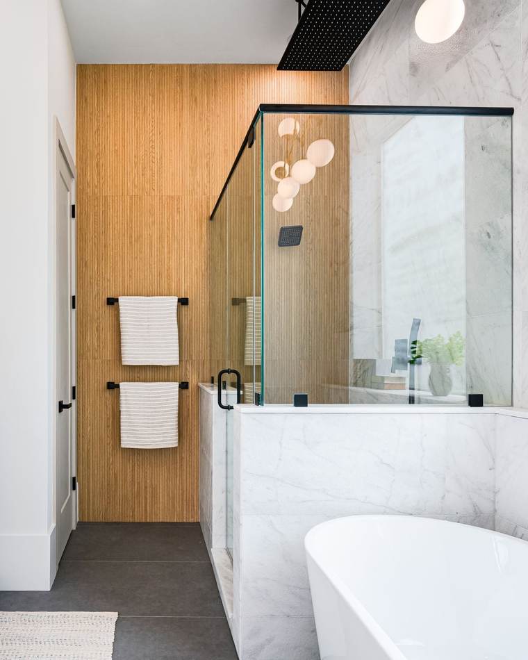 Primary bathroom with a white double vanity, arched gold mirrors, a glass walk-in shower and a freestanding tub