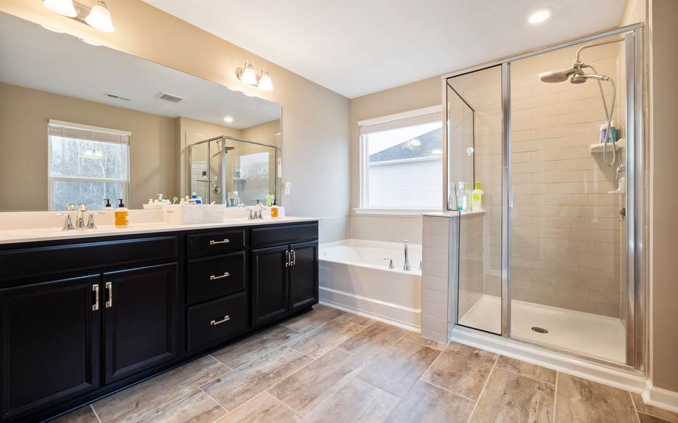 Primary bathroom with a double vanity and a tiled walk-in shower behind glass