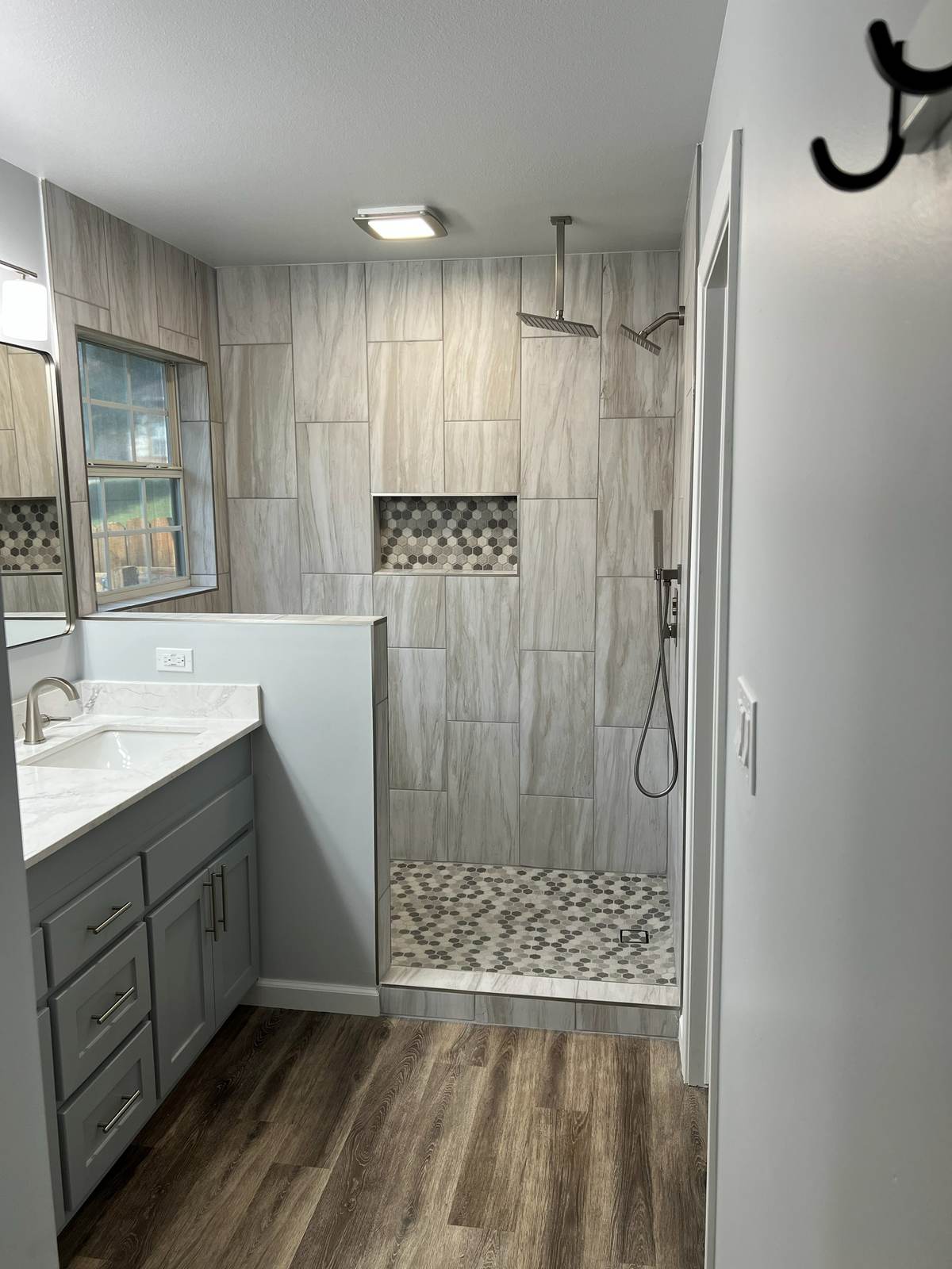 The new walk-in shower behind its half wall, beside the refinished vanity, in the Tulsa master bathroom