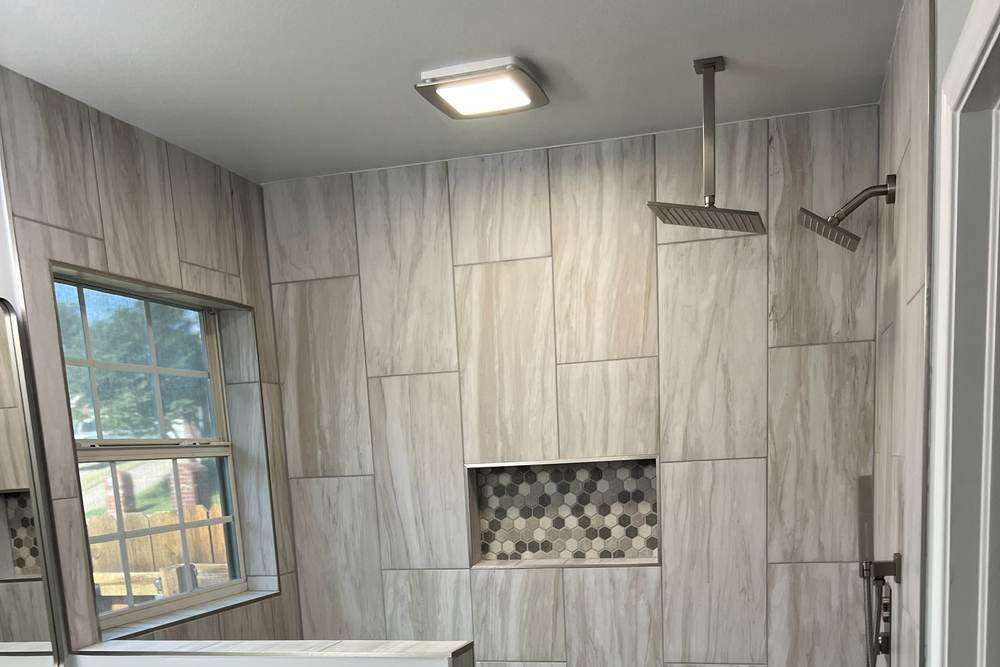 Ceiling exhaust fan and light above a tiled walk-in shower with a hex tile niche, put in during the east Tulsa master bath remodel where a garden tub became this shower