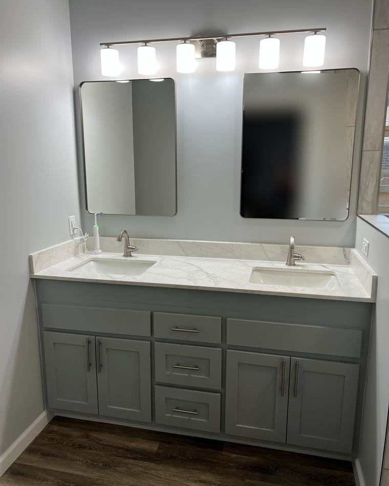 After: a gray shaker double vanity with a marble-look top, two mirrors and a light bar