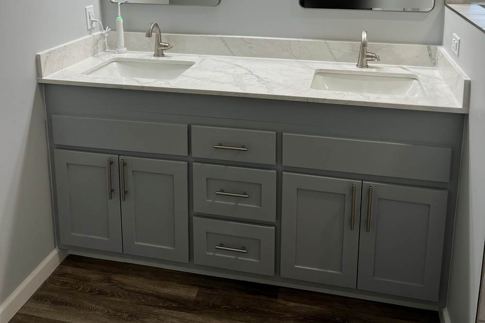 Gray double vanity with a marble-look quartz top, two framed mirrors and a light bar over a vinyl plank floor, in an east Tulsa master bath we remodeled