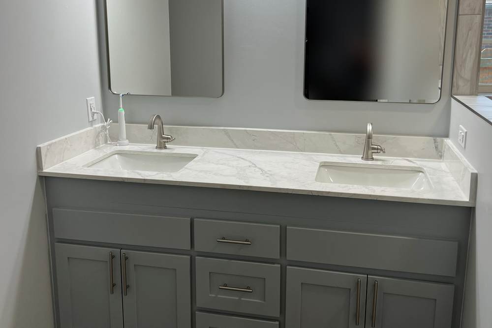 Gray double vanity with a marble-look quartz top and two framed mirrors, the cabinet we raised six inches in an east Tulsa master bath
