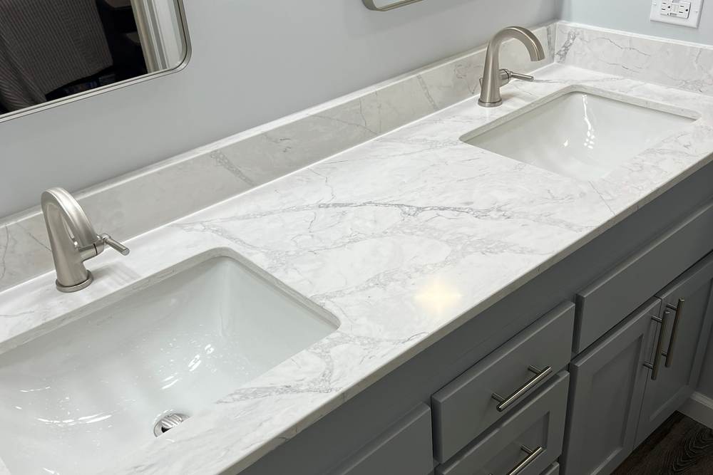 Marble-look quartz vanity top with two undermount sinks and brushed nickel faucets, chosen by the homeowners in an east Tulsa master bath we remodeled