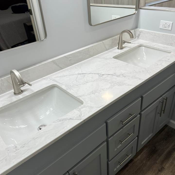 A marble-look vanity top with two undermount sinks and brushed nickel faucets