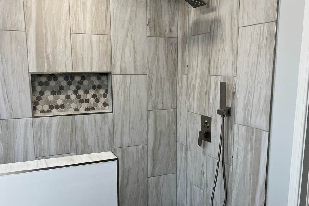 Rain head and hand shower with matte black trim on wood-look gray tile, in a shower we built in east Tulsa