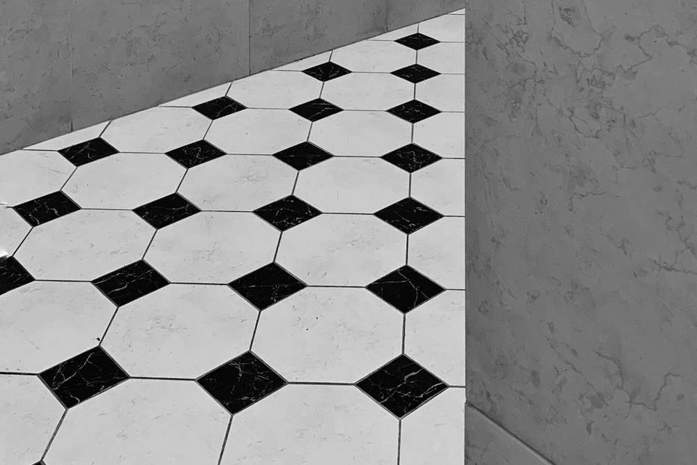 Black and white octagon and dot floor tile beside a gray stone-look wall