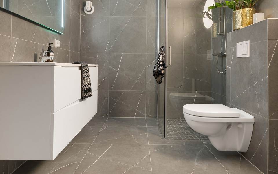 Restroom with large gray porcelain floor tile, a floating white vanity and a wall-hung toilet