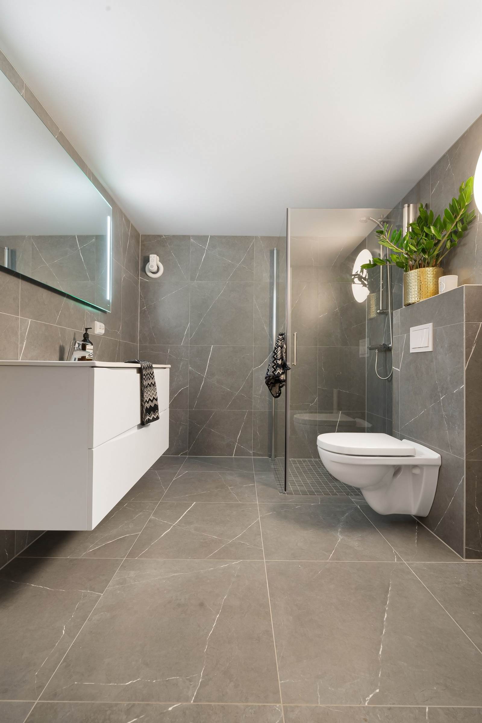 Bathroom with a large matte gray porcelain floor, a curbless glass shower and a floating white vanity