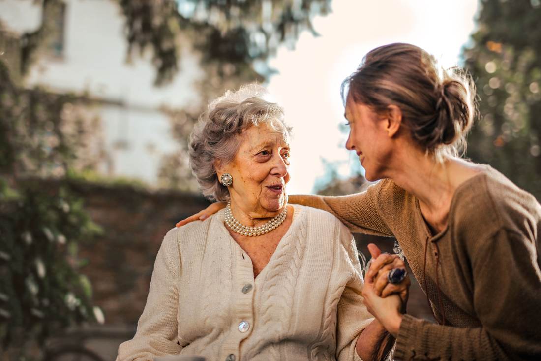 Adult daughter smiling with her senior mother, holding her hand