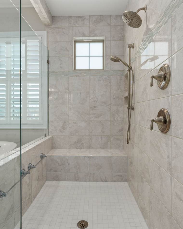 Bright tiled walk-in shower with a built-in bench, a hand shower on a slide bar and a small-tile floor