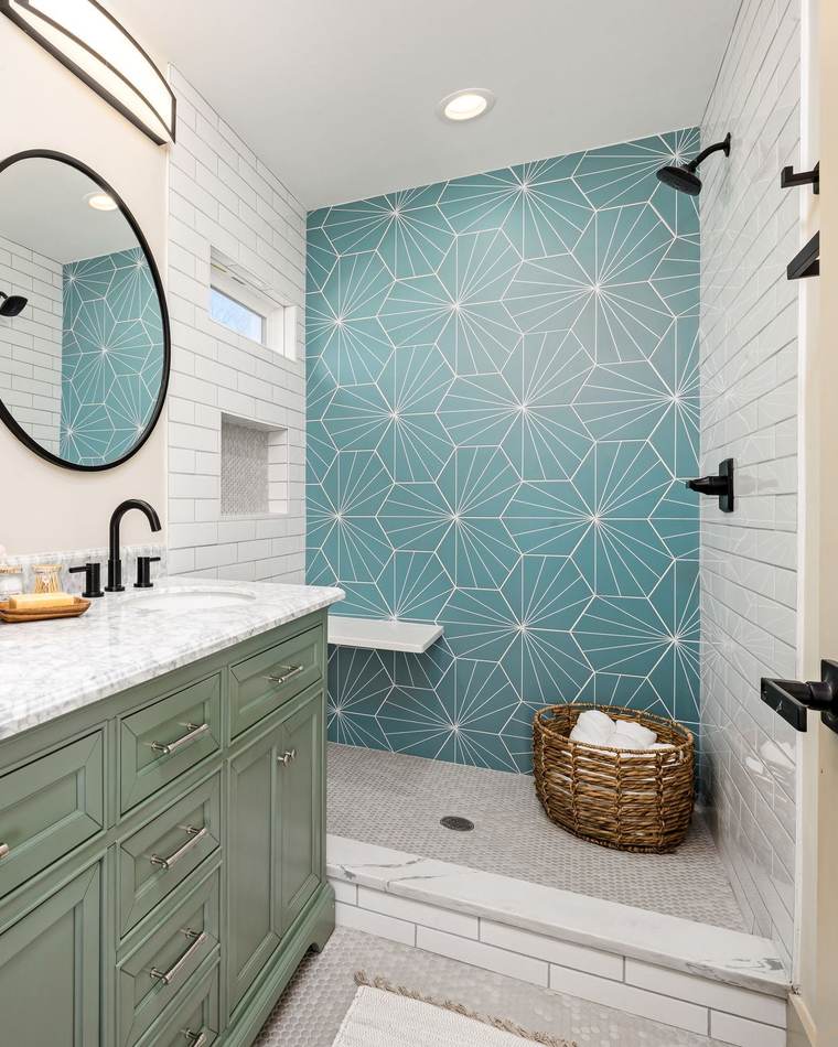 Bright bathroom with a green double vanity beside a tiled walk-in shower with a low curb, a teal patterned wall and a built-in bench