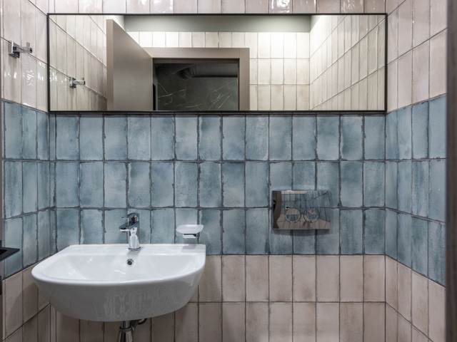 Single-user restroom with blue handmade-look wall tile, a wall-hung sink and a long mirror