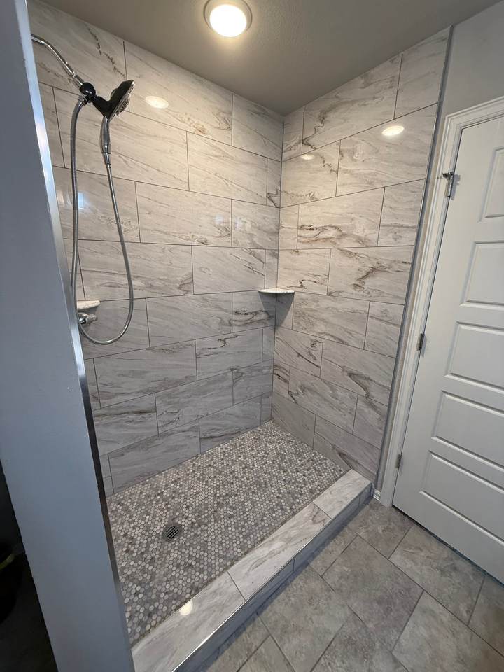 A compact walk-in shower with a tile curb and corner shelves