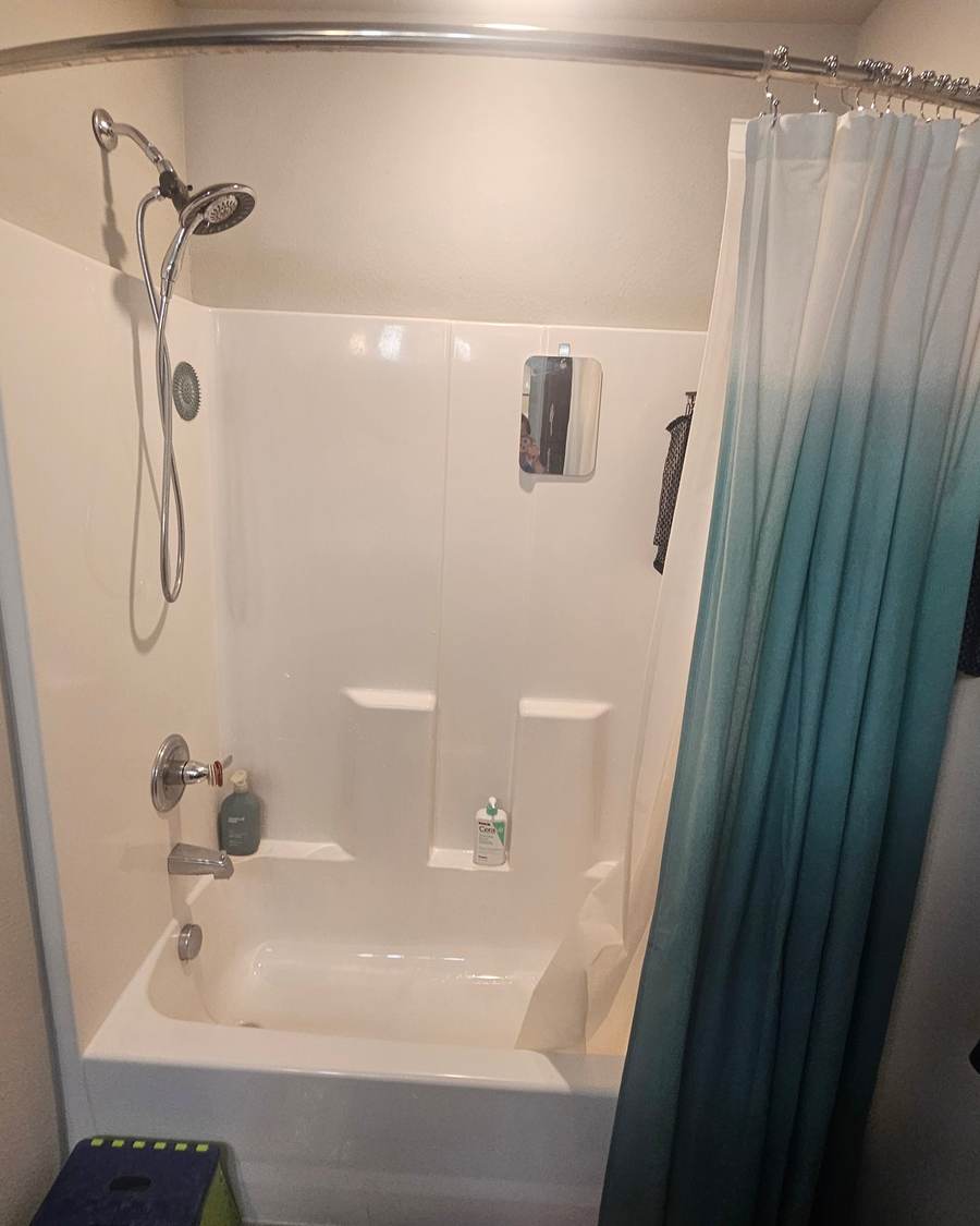 Before: a white fiberglass tub and shower combo with a curved curtain rod in a Bixby bathroom