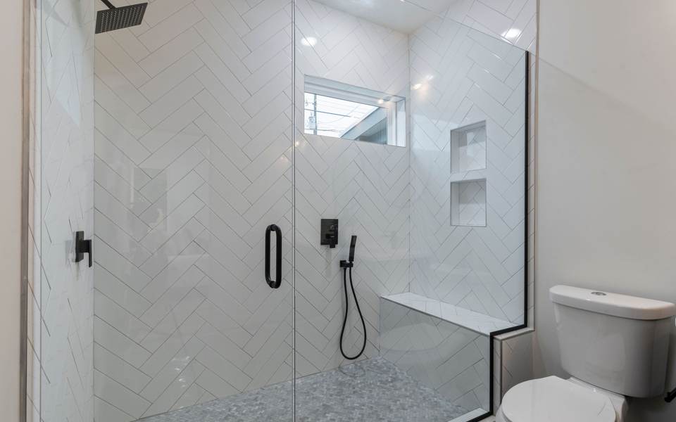 Walk-in shower with white herringbone wall tile, a built-in bench and a frameless glass door