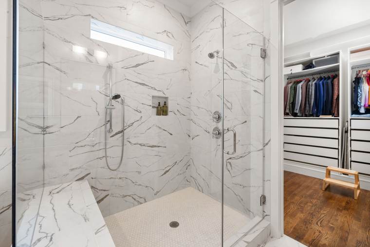 Walk-in shower with marble-look tile, a built-in bench, and a frameless glass enclosure