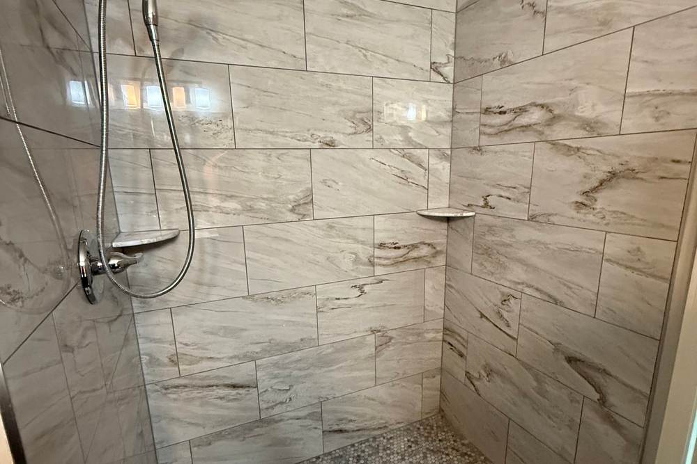 Hand shower on a slide bar and corner shelves in a walk-in shower we built where a tub used to be, in Bixby